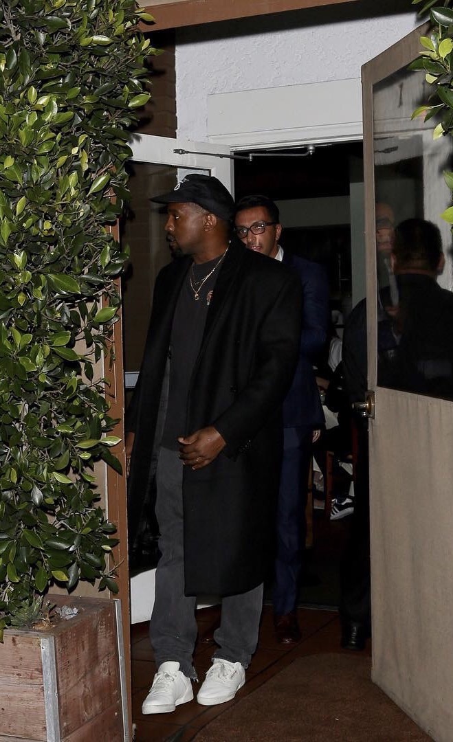 SPOTTED: Kanye West In Adidas Yeezy Season Shirt And Sneakers, Public Enemy Hat And Longline Coat