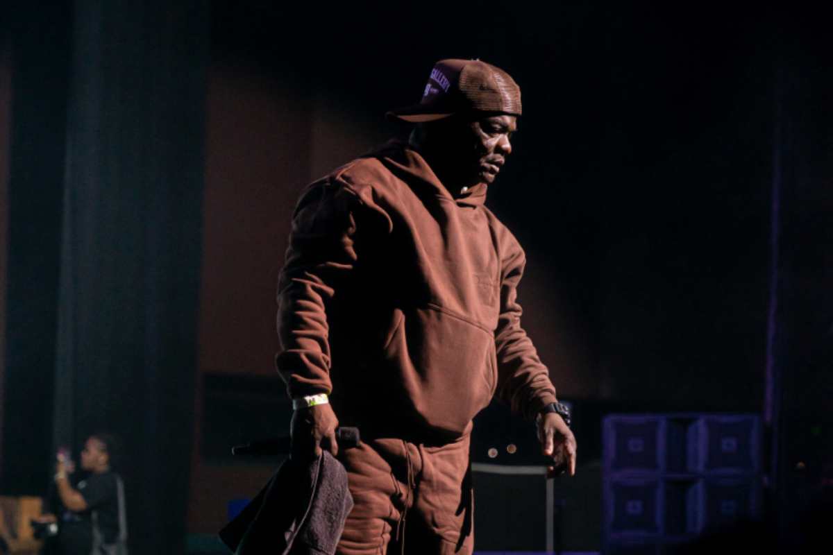 Spotted Comedian Larry Dogg on Stage at the “Never Give Up Tour” Wearing Oceans Gallery Modern Distinct Trucker Hat and French Terry Sweatsuit
